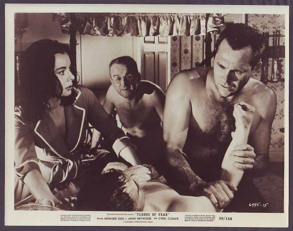 Howard Keel (on right) attends to an injured man while Anne Heywood and Cyril Cusack look on in Floods of Fear (1958), directed by Charles Crichton