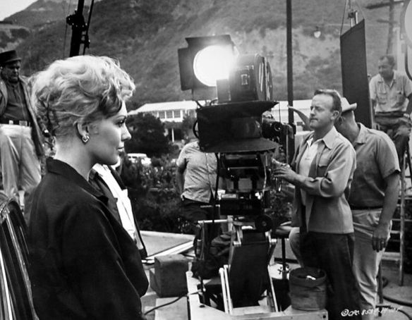 Kim Novak on the set of Strangers When We Meet (1960), with director Richard Quine in the background adjusting her lighting